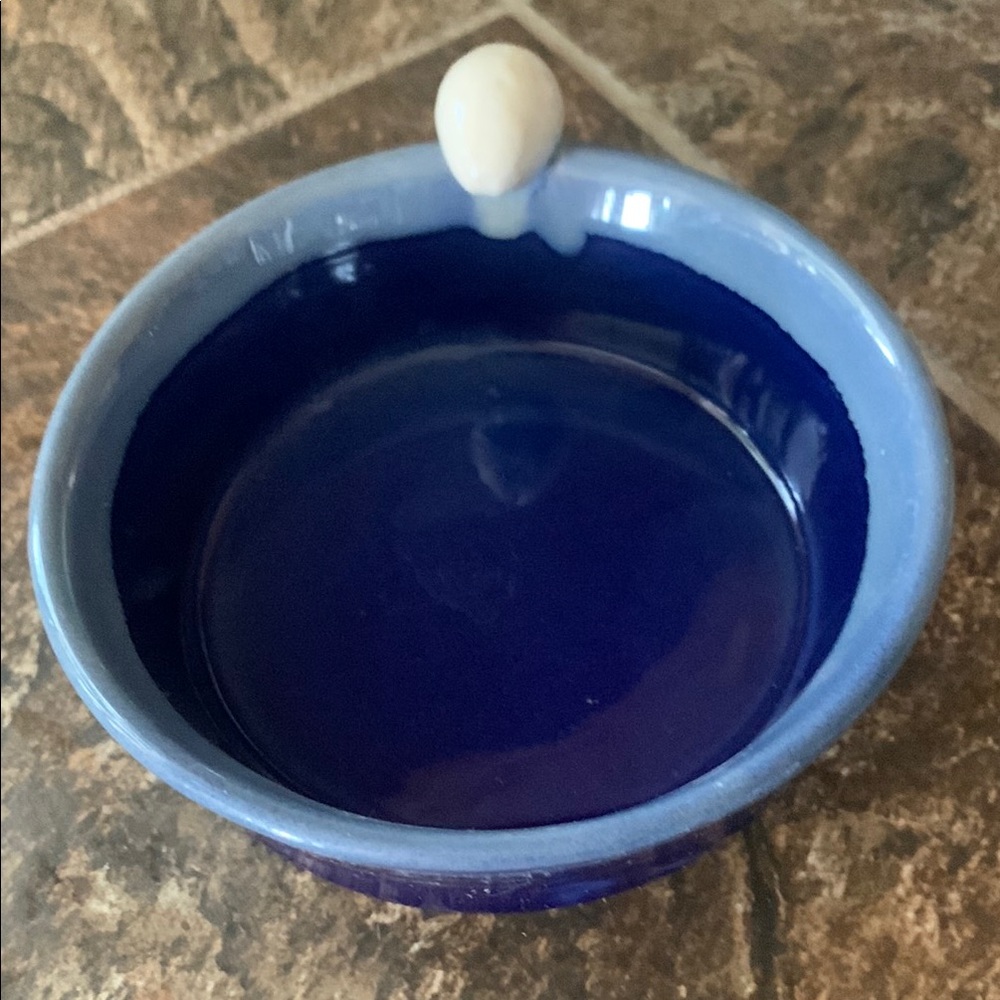 Tumbleweed pottery.  Two tone blue bowl with whimsical tan egg on rim